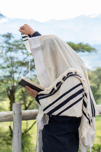 Foto judeu rezando e lendo o sidur enquanto levanta o braço direito para o céu