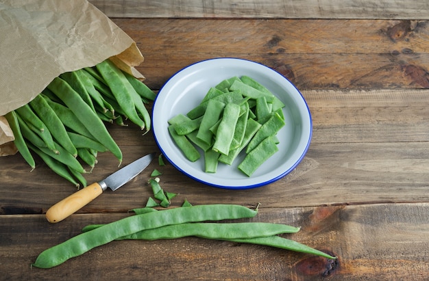 Judías verdes enteras y cortadas sobre fondo de madera. Ingredientes de la comida. Vista superior.