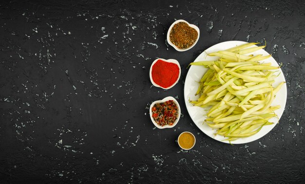 Judías verdes frescas en un plato sazonado en una mesa oscura. Vista desde arriba. Copia espacio