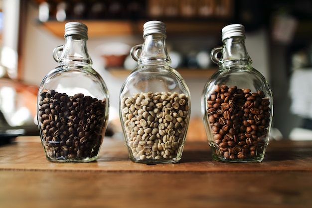 Foto judías verdes y granos de café, asado de la ciudad en la botella transparente, enfoque único sujeto borroso b