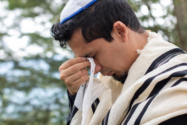Un judío realiza un ritual religioso de oración sosteniendo el Tzitzit en sus ojos mientras reza a su dios.