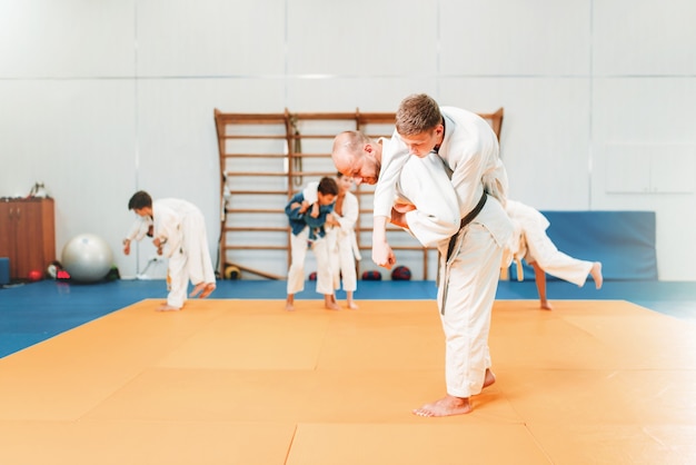 Judo infantil, jóvenes luchadores en entrenamiento en el pasillo. Los niños pequeños en kimono practican artes marciales.