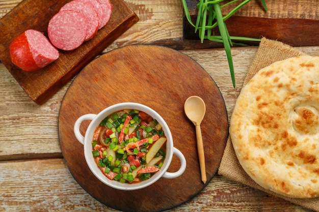 Jüdische Khni-Cholit-Bohnensuppe auf einem runden Stand neben Frühlingszwiebelwurst und Brot