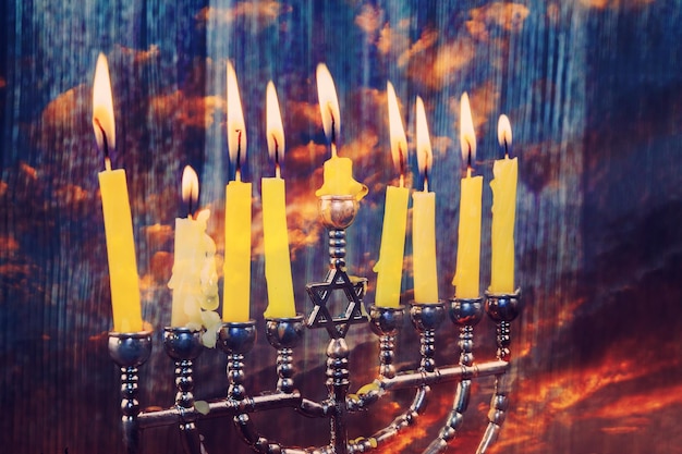 Jüdischer Feiertag Chanukka mit traditioneller Menorah und hölzernen Dreidels, die sich oben glänzen