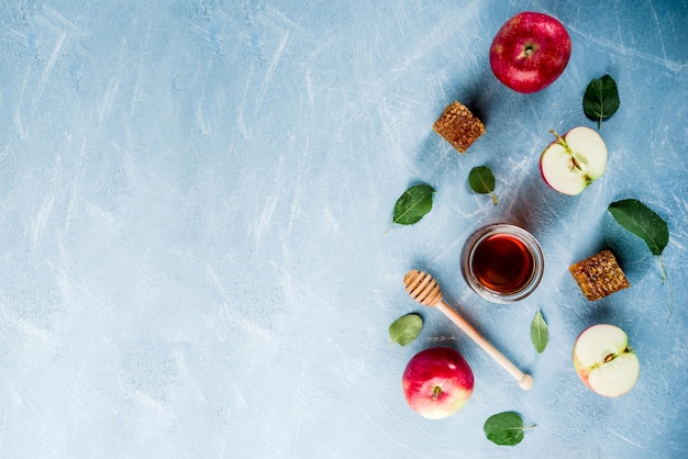 Jüdischer Feiertag Rosh Hashanah oder Apfelfest-Tageskonzept, mit roten Äpfeln, Apfelblättern und Honig im Glas