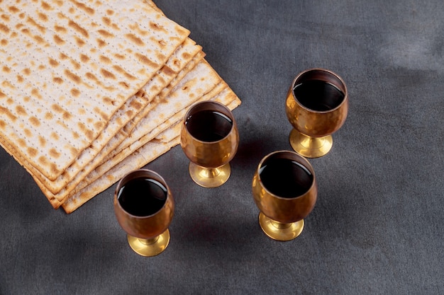 Jüdisches Feiertagsbrot des Passahfesthintergrundes vier Wein und Matzoh über hölzernem Brett.