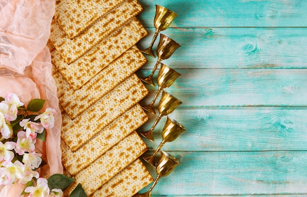 Jüdisches Matzebrot auf Holz mit sechs Weinbechern und Blumen. Pessachferienkonzept