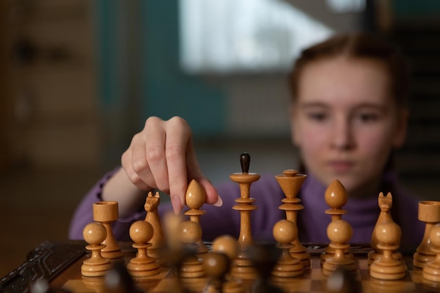 Un juego de ajedrez La niña sostiene un peón en sus manos Estilo fotográfico dramático oscuro en colores oscuros