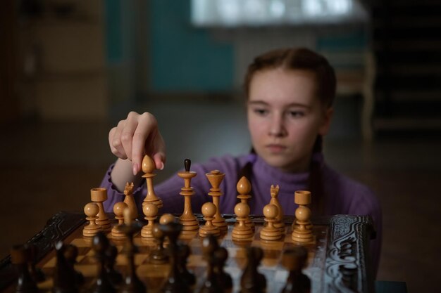 Un juego de ajedrez La niña sostiene un peón en sus manos Estilo fotográfico dramático oscuro en colores oscuros