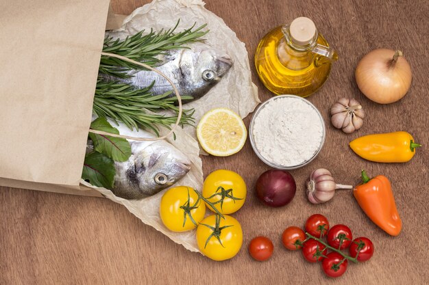 Juego de alimentos. Bolsa de papel con pescado crudo y verduras.