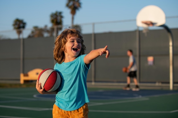 Juego de baloncesto para niños Lindo niño riendo y sosteniendo una pelota de baloncesto tratando de hacer una puntuación riendo Niño señalando mostrando gesto