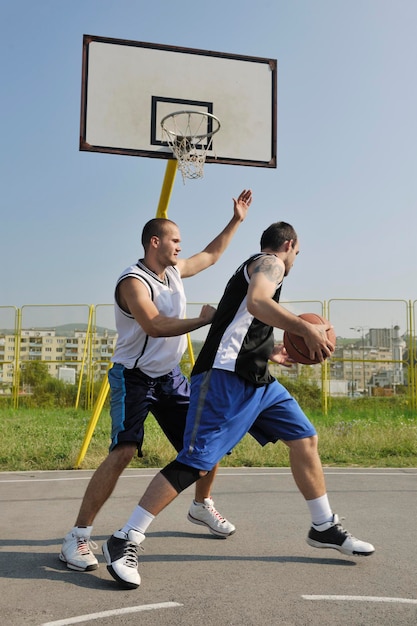 juego de baloncesto streetball con dos jugadores jóvenes temprano en la mañana en la cancha de la ciudad