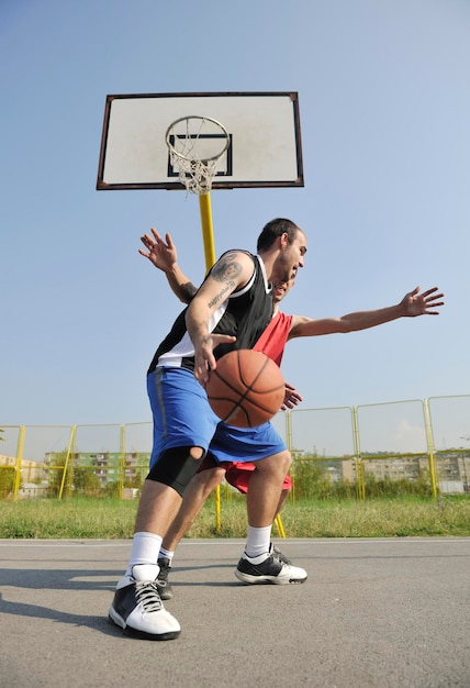 juego de baloncesto streetball con dos jugadores jóvenes temprano en la mañana en la cancha de la ciudad