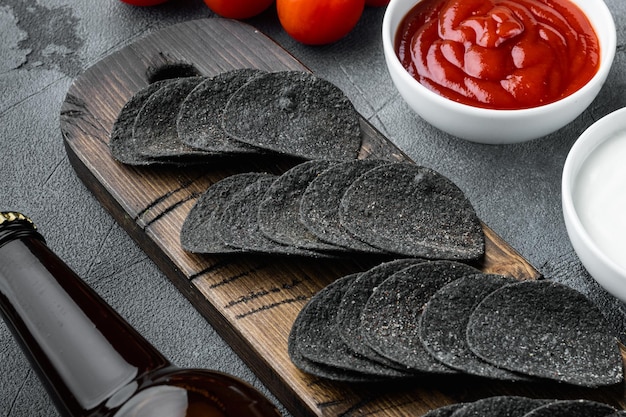 Juego de bocadillos crujientes de queso y cebollino, con salsas para mojar, salsa de tomate, crema agria y una botella de cerveza, sobre fondo de piedra gris