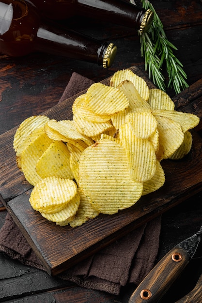 Juego de bocadillos de papas fritas saladas, sobre la vieja mesa de madera oscura.