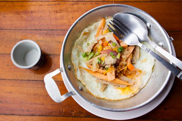 Juego de comida para el desayuno, huevo frito con aderezos, salchichas y verduras en una sartén pequeña en el restaurante local, cafetería, tienda para viajeros tailandeses, servicio de uso al cliente, comer bebidas en Ratchaburi, Tailandia