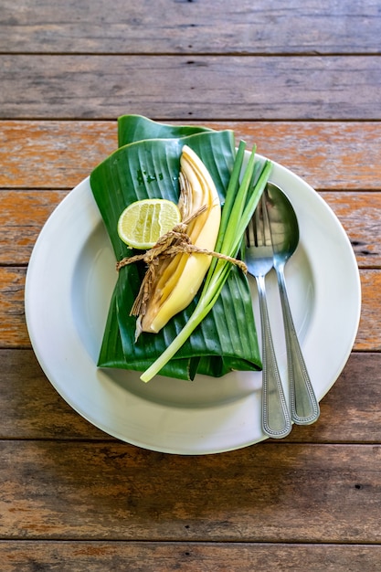 Juego de comida tailandesa envuelto cubierto por hoja de plátano listo para servir. Dentro de la hoja de plátano está PadThai, el tradicional fideo frito de Tailandia con gambas.