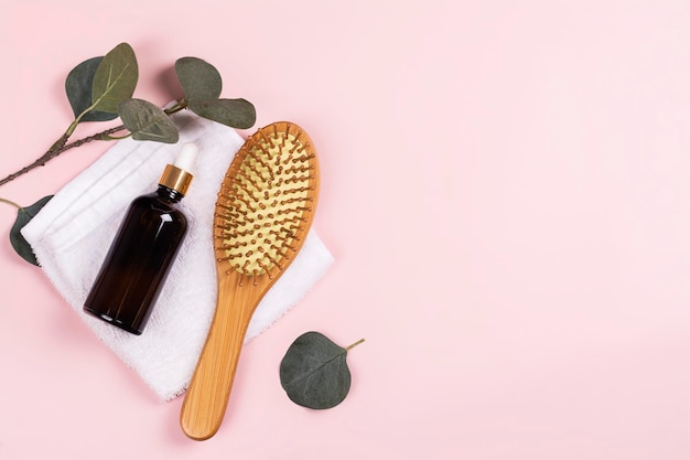 Foto el juego de cuidado del cabello cepillo de bambú y aceite para el cabello en rosa