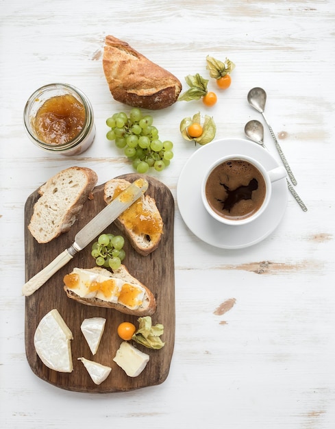 Juego de desayuno Sándwiches de queso Brie y mermelada de higo con uvas frescas cerezas molidas Taza de café Vista superior