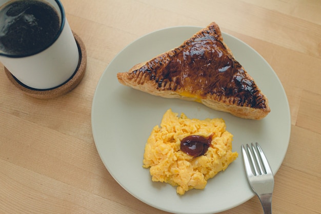 Juego de desayuno de tarta de sándwich casera con huevos revueltos y café negro.