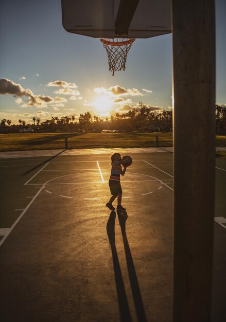Juego de entrenamiento de baloncesto para niños en silueta puesta de sol