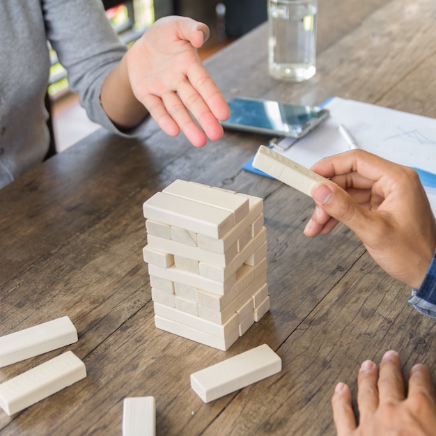 Foto juego de habilidad física y mental. mantén el balance. niña construye la torre de bloques de madera. actividad de entretenimiento. educación, desarrollo. las chicas recogen una constricción extensa de bloques de madera