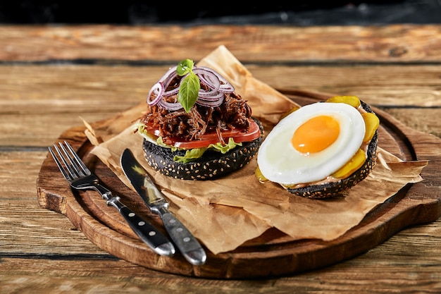 Juego de hamburguesa con huevo y cerveza. Un conjunto estándar de bebidas y comida en el pub, cerveza y bocadillos. Fondo oscuro, comida rápida. Comida tradicional americana.