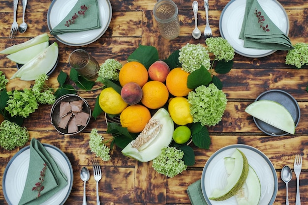 Juego de mesa de verano Comedor al aire libre Mesa de madera decorada con flores frescas y frutas de verano