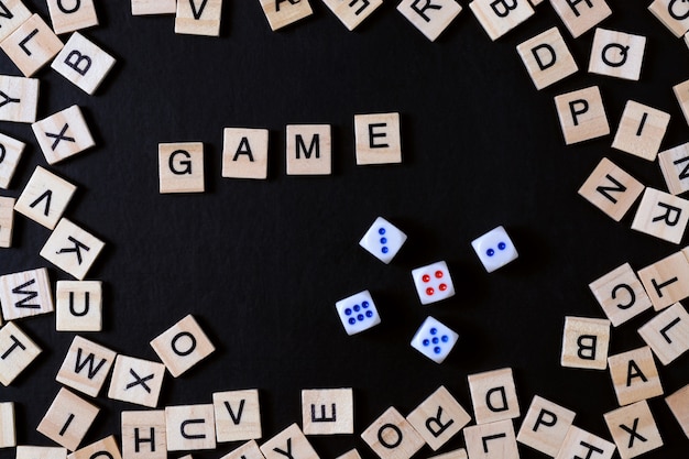 Foto juego de palabras con letras de madera en tablero negro con dados y letra en el círculo