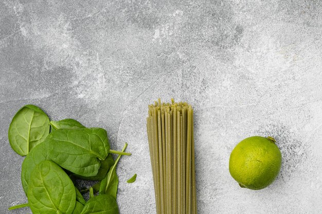 Juego de pasta de color verde espinaca, sobre fondo de mesa de piedra gris, vista superior plana, con espacio para copiar texto