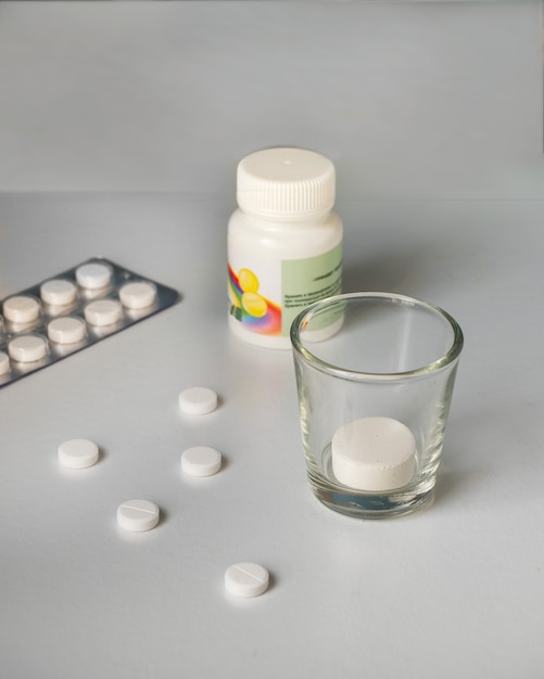 Un juego de pastillas y un vaso de vidrio para tomar medicamentos para el tratamiento de enfermedades virales.