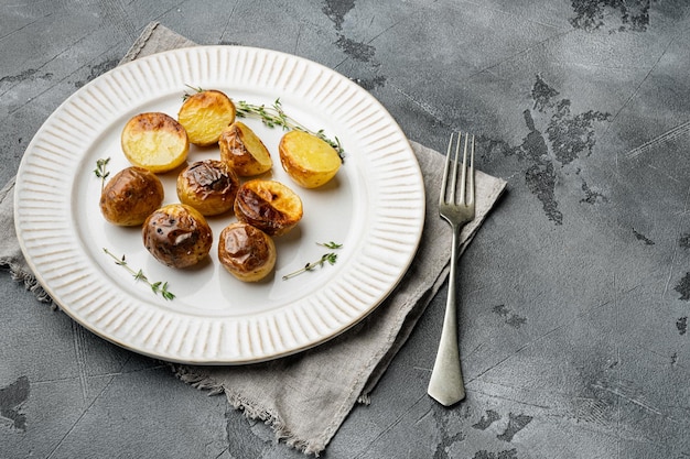 Juego de patatas al horno, en plato, sobre fondo de mesa de piedra gris, con espacio para copiar texto