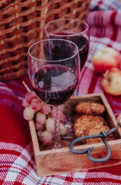 Juego de picnic al aire libre de otoño Una botella de vino tinto, dos copas de vino, manzana de uva a cuadros y galletas