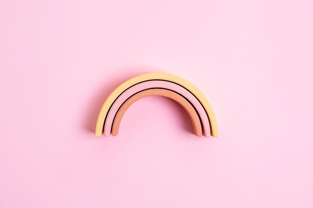 Foto juego de pirámide de pastel de juguete de arco de niño de educación sobre fondo rosa figura de madera colorida sobre fondo amarillo concepto de juego de niños