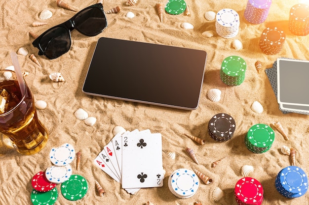 Juego de póquer en línea en la playa con tableta digital y pilas de fichas vista superior