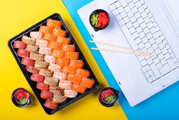 Un juego de rollos de sushi y una computadora portátil en la oficina almuerzo japonés en el trabajo