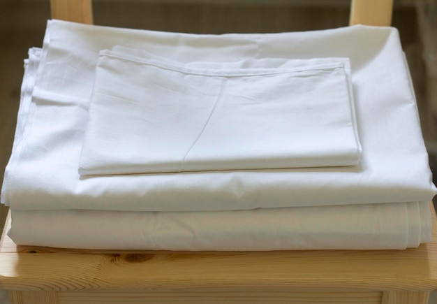 Un juego de ropa de cama blanca está acostado sobre una silla.