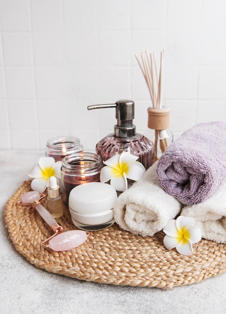 Juego de spa, aceite esencial, sal de masaje, velas y flores de frangipani sobre fondo de hormigón gris