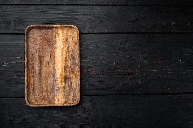 Juego de tabla de cortar de madera vacía, vista superior plana, con espacio para copiar texto o su producto, sobre fondo de mesa de madera negra