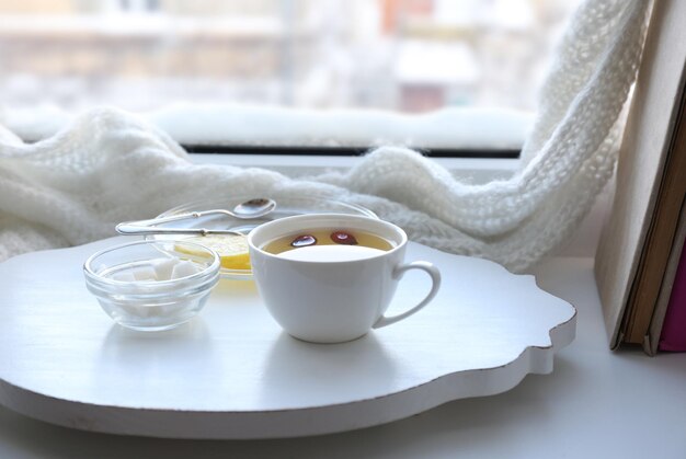 Juego de té en una bandeja de madera blanca en el alféizar de la ventana