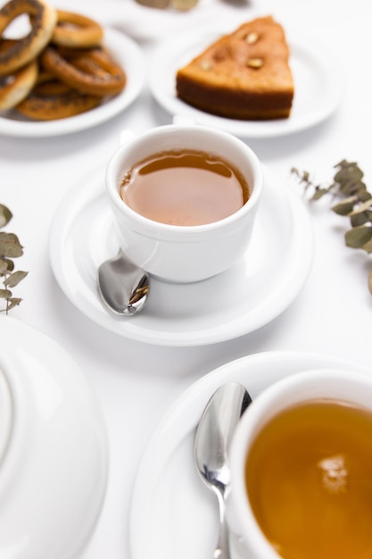 Juego de té blanco con té de tetera y platillos y pastel para el desayuno