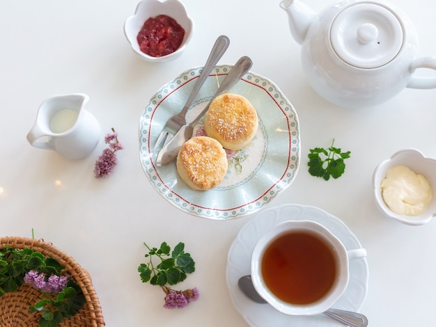 Juego de té de desayuno con galletas frescas, mantequilla, mermelada.