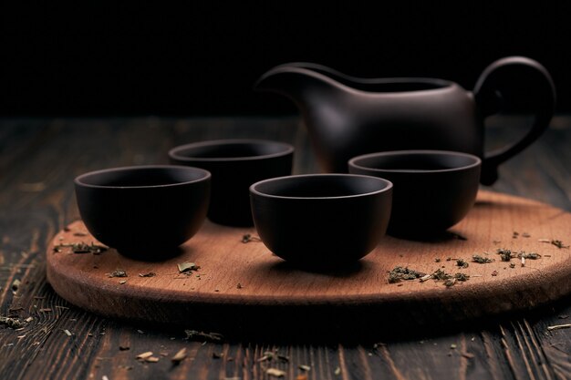 Juego de té y hojas de té en la placa de cocina de madera