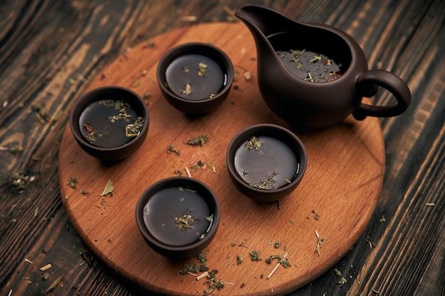 Juego de té y hojas de té sobre fondo de madera