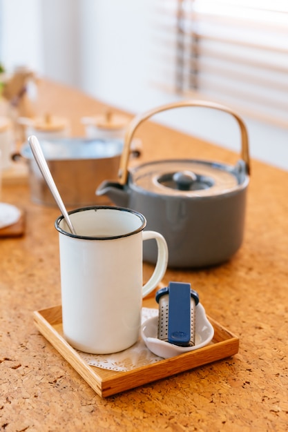 El juego de té de la tarde sirvió agua caliente en una olla gris con taza de lata e infusor de té.