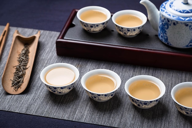 Un juego de té con tazas de té y una tetera sobre una mesa.