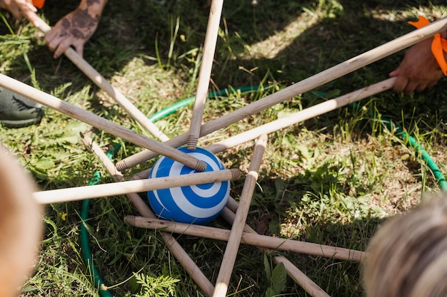 Juego de teambuilding para grupos de personas para fomentar el espíritu de equipo y aumentar la amistad de los compañeros. Juego de equipo con pelota y palos.