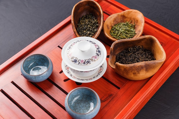 El juego de tetera, tres tipos de té y dos tazones en el escritorio del té están listos para la ceremonia del té.