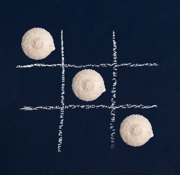 Juego de tictactoe con galletas blancas sobre fondo negro