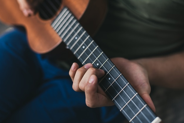 Juego de ukelele. Un hombre tocando una pequeña guitarra. el intérprete escribe la música en el ukelele en casa